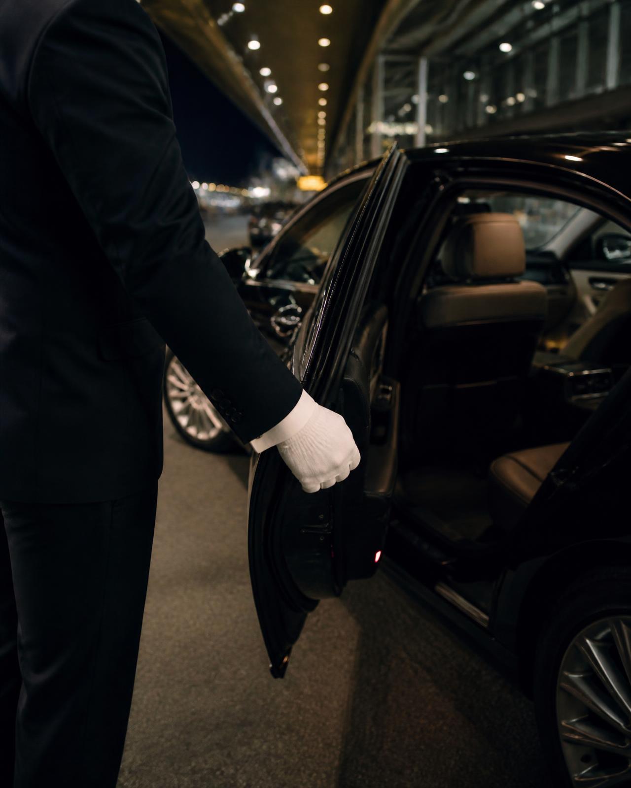 Chauffeur opening the door of a luxury car at an airport terminal